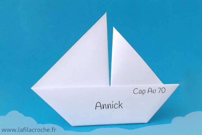 Un marque-place voilier origami personnalisé avec un texte court sur le haut de la coque