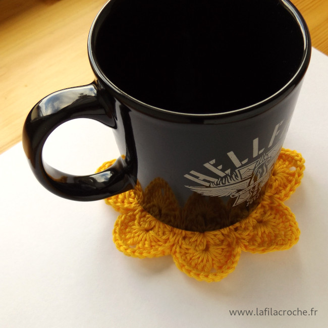 Un gros mug posé sur un dessous de tasse fleur en crochet
