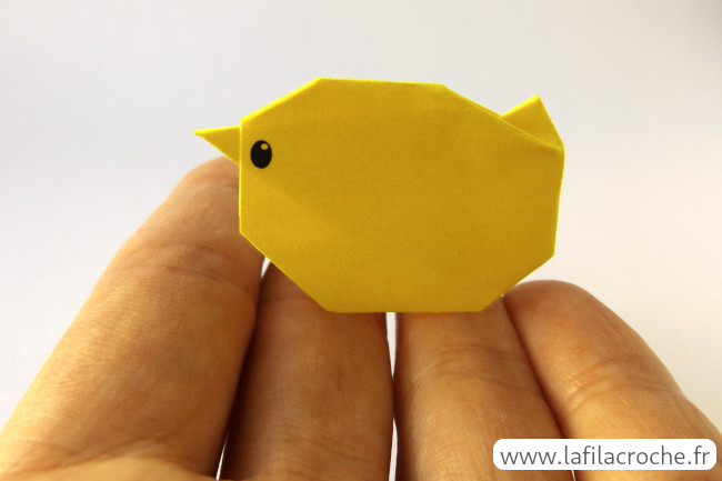 Un petit poussin en origami posé sur une main