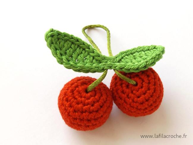 Deux petites cerises au crochet avec leur feuille et un cordon pour les suspendre